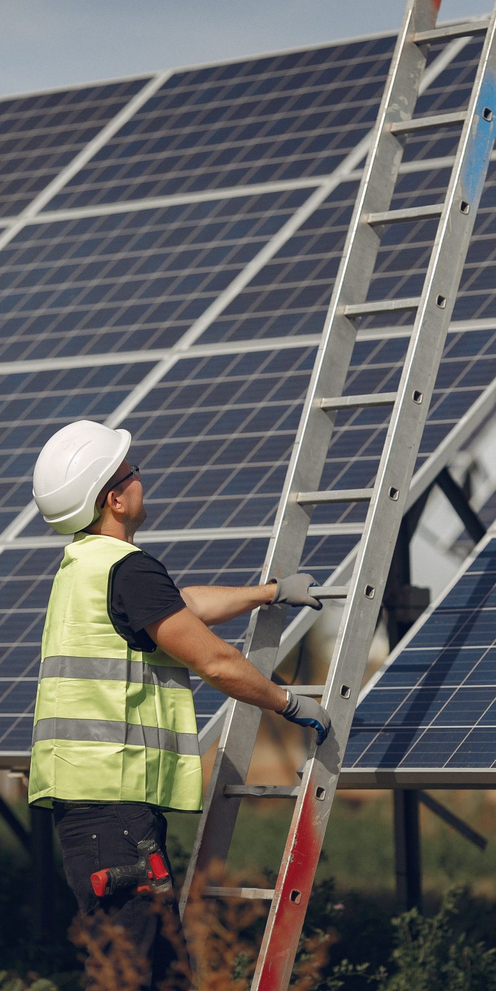 Engineer in a white helmet. Man near solar panel. Worker with a ladder